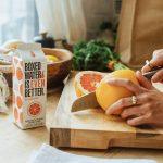 a person cutting an orange on a cutting board
